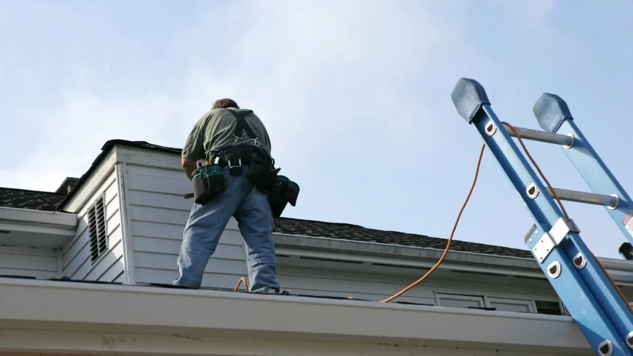 Wchodzenie na dach i chodzenie po dachu - jak robić to bezpiecznie. Zdjęciep rzedstawia człowieka chodzącego po dachu z odpowiednim zabezpieczeniem w postaci lin.