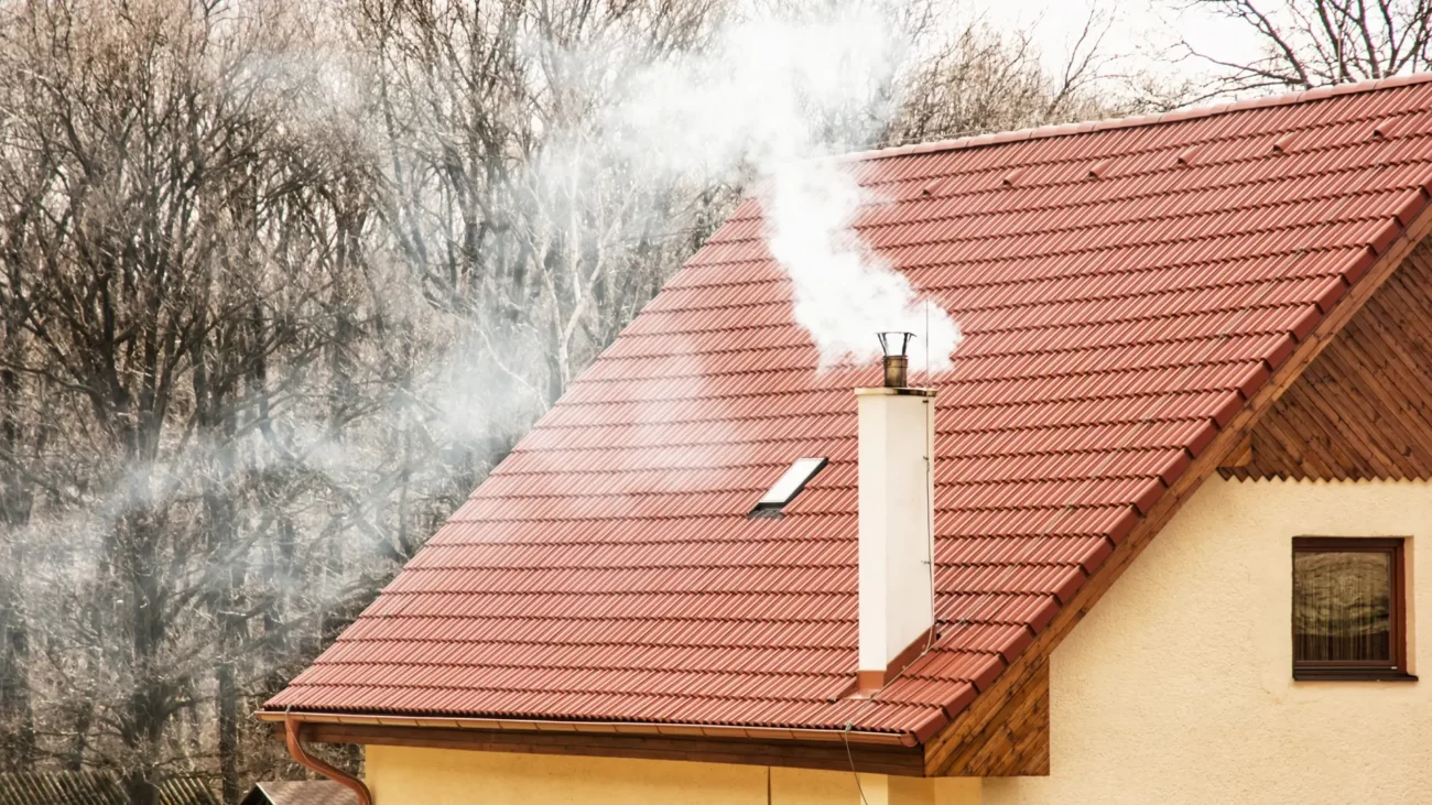 Obróbka blacharska komina - jak ją wykonać? Zdjęcie porzedstawia komin i otoczające go prawidłowo stworzone i zamontowane obróbki blacharskie komina